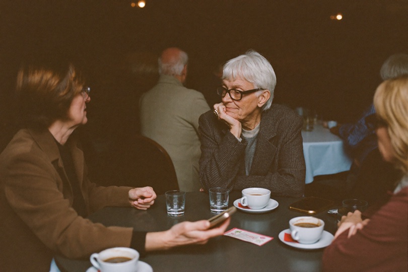 Ouderen in gesprek aan tafeltjes tijdens een gezellige caféavond