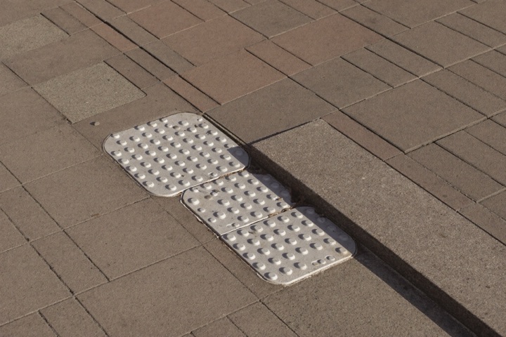 Verlaagde stoeprand met geleidelijnen op een vernieuwd trottoir
