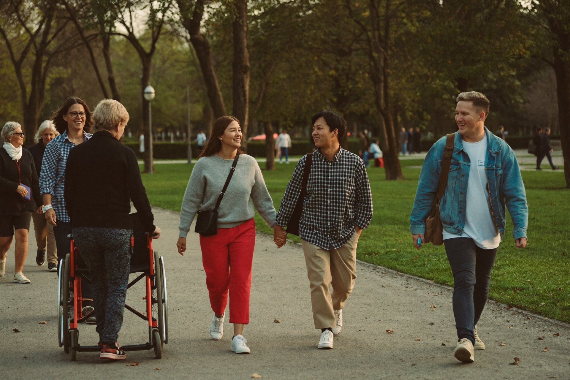 Een diverse groep mensen, onder wie een rolstoelgebruiker, wandelt samen door een park in Heerlen