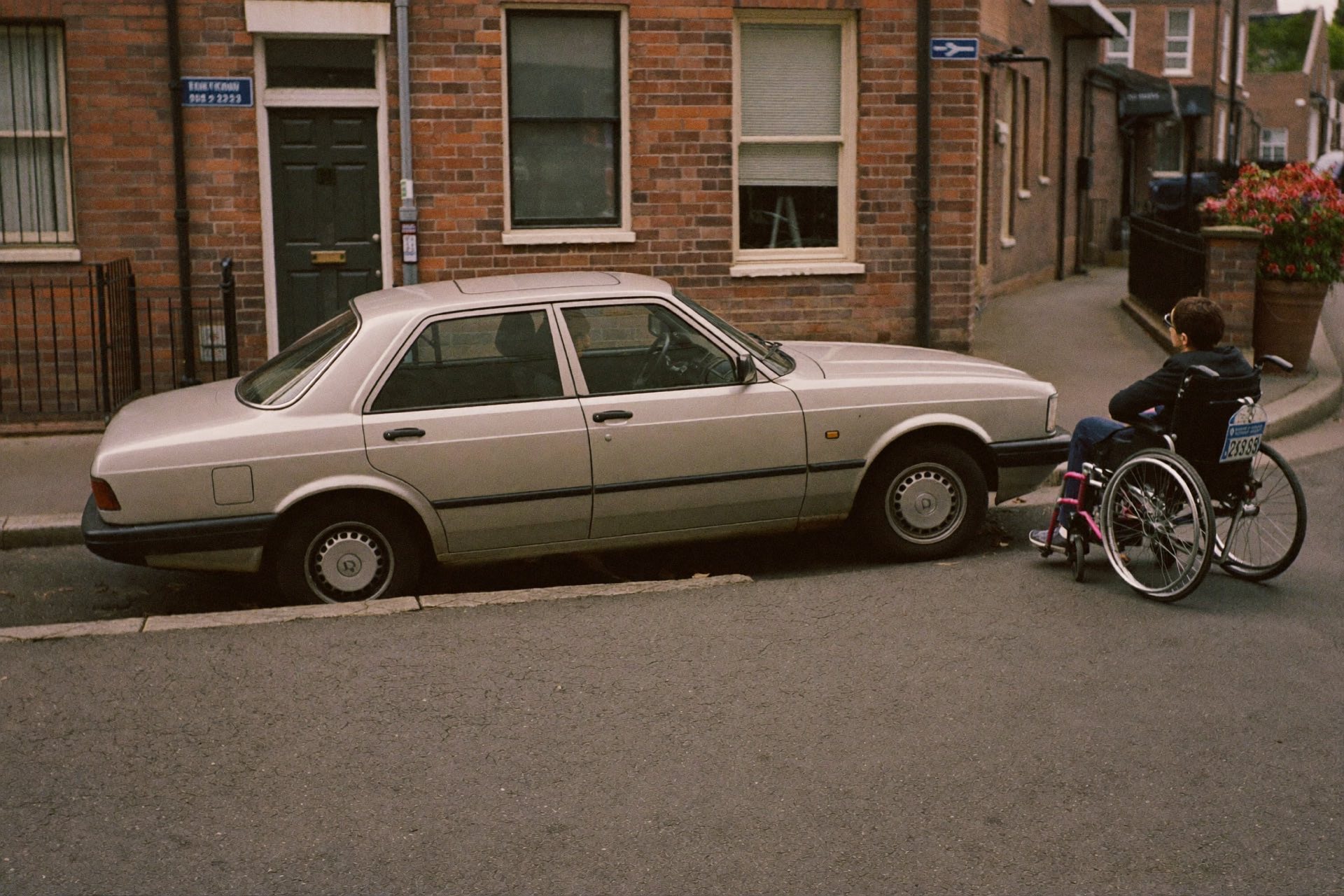 Auto's staan half op de stoep geparkeerd, een rolstoelgebruiker kan er niet langs